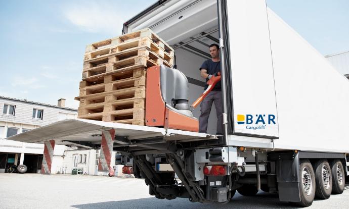 Piattaforma di carico BAR aperta e accessibile, sulla quale una persona spinge un pallet vuoto nel veicolo