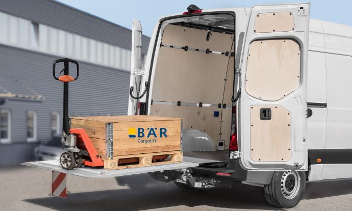 Sulla piattaforma ribaltata e sollevata del Bar VanLift si trova un pallet con un transpallet