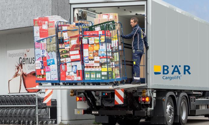 Un camionista scarica diversi contenitori per alimenti dal camion davanti al negozio di alimentari con l'aiuto del Bar Cargolift
